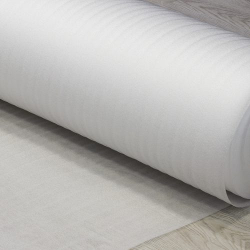Rolled white foam underlay on wooden flooring, perfect for insulation, soundproofing, and cushioning.